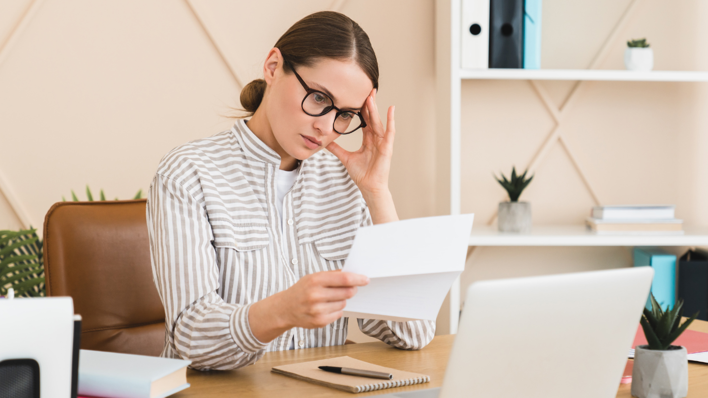 Mujer estresada mirando un documento impreso pensando en la renegociación administrativa